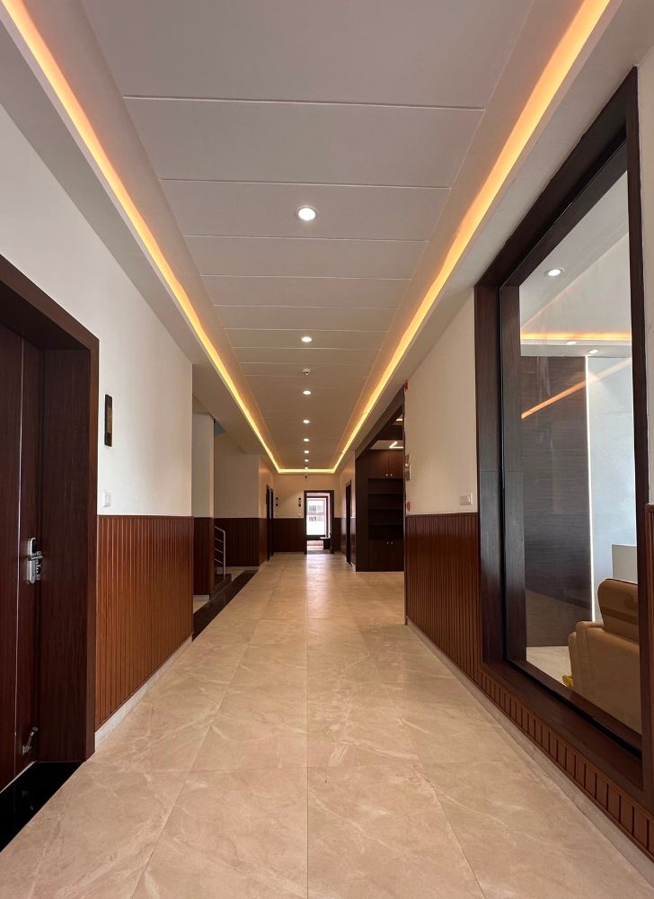 Modern residential corridor interior designed by Design Plus Architects, featuring elegant wooden wall paneling, ambient ceiling lighting, and contemporary finishes in Namakkal.
