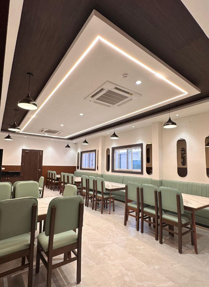Modern restaurant interior designed by Design Plus Architects, featuring elegant dining seating, designer false ceiling, ambient LED lighting, and contemporary hospitality interiors in Namakkal.